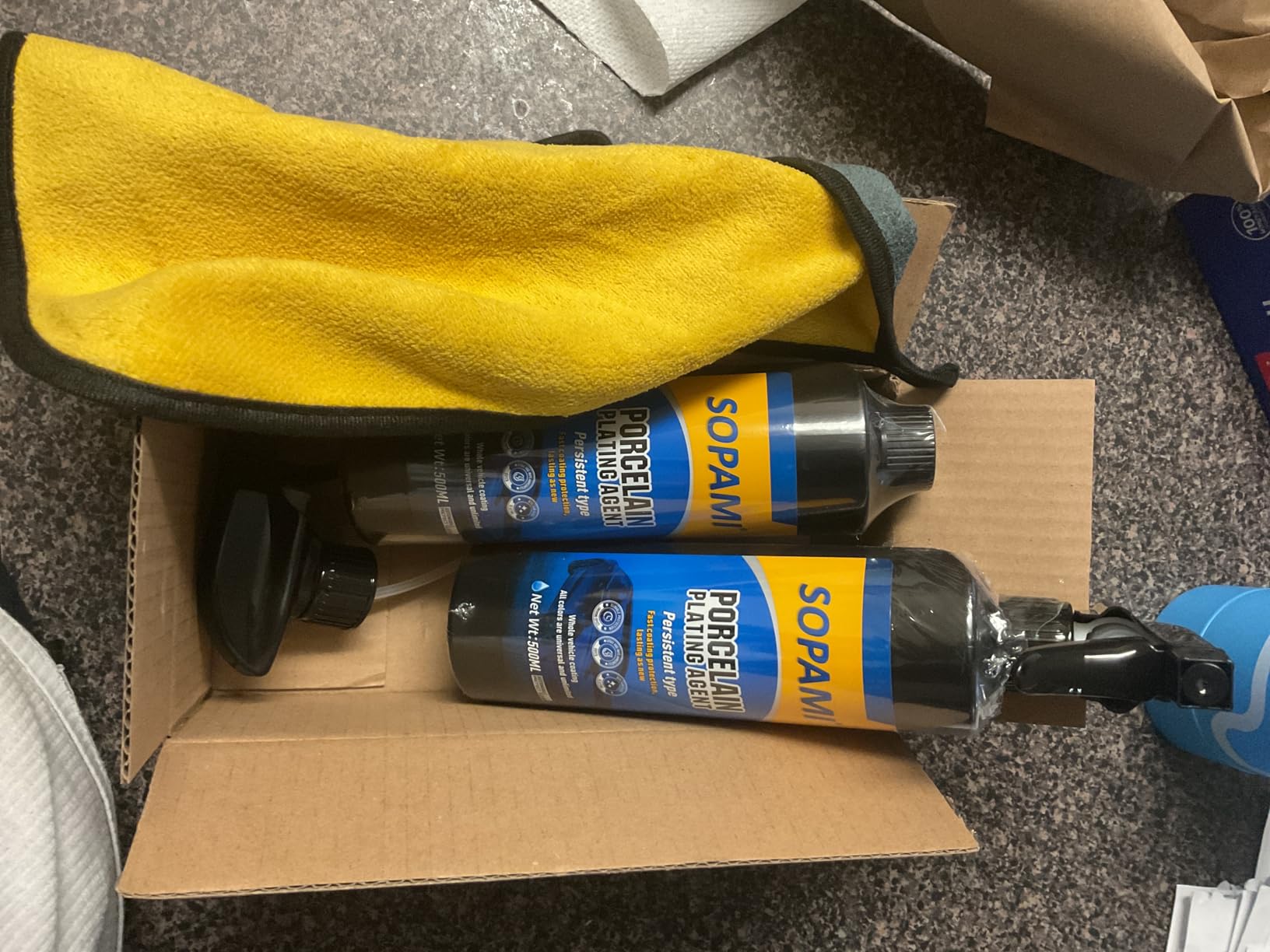 Two 500 ml Sopami Porcelain Plating Agent bottles in an opened shipping box with the yellow and gray microfiber towel