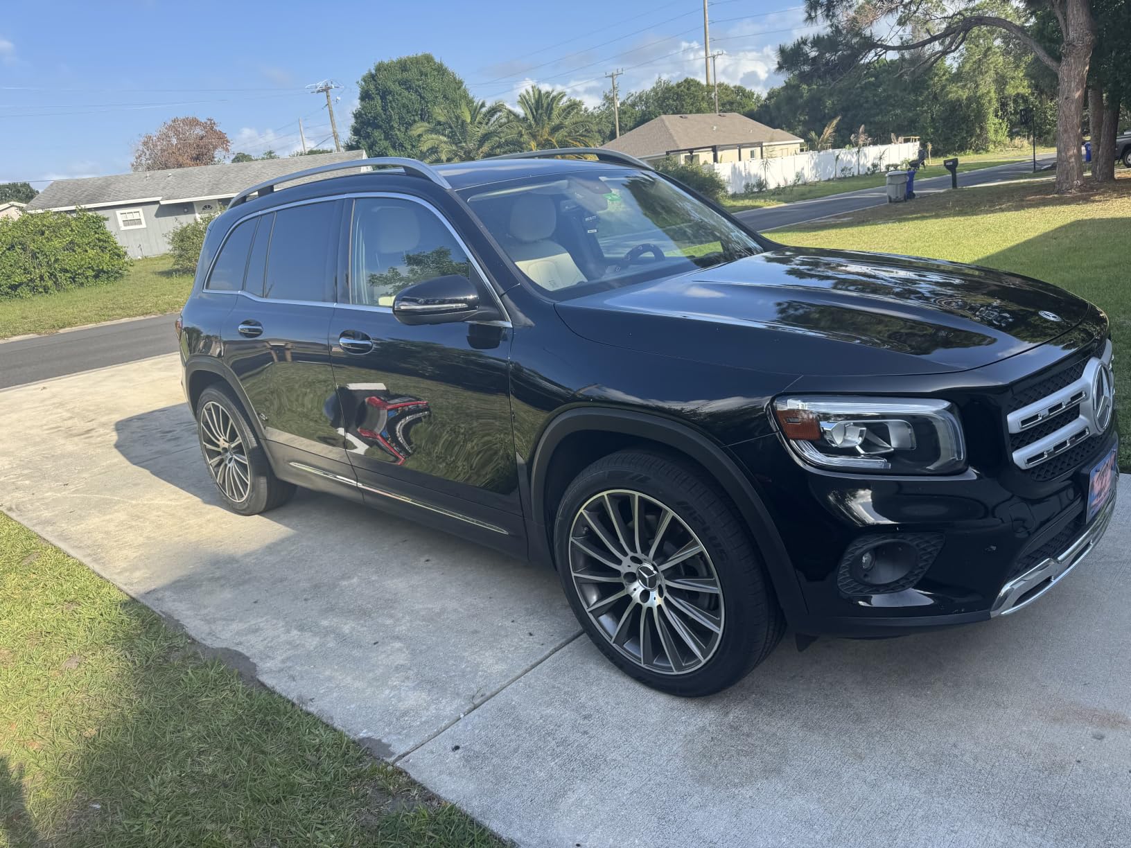 Black Mercedes GLB on a driveway, the doors reflecting the house and lawn without any haze in the paint